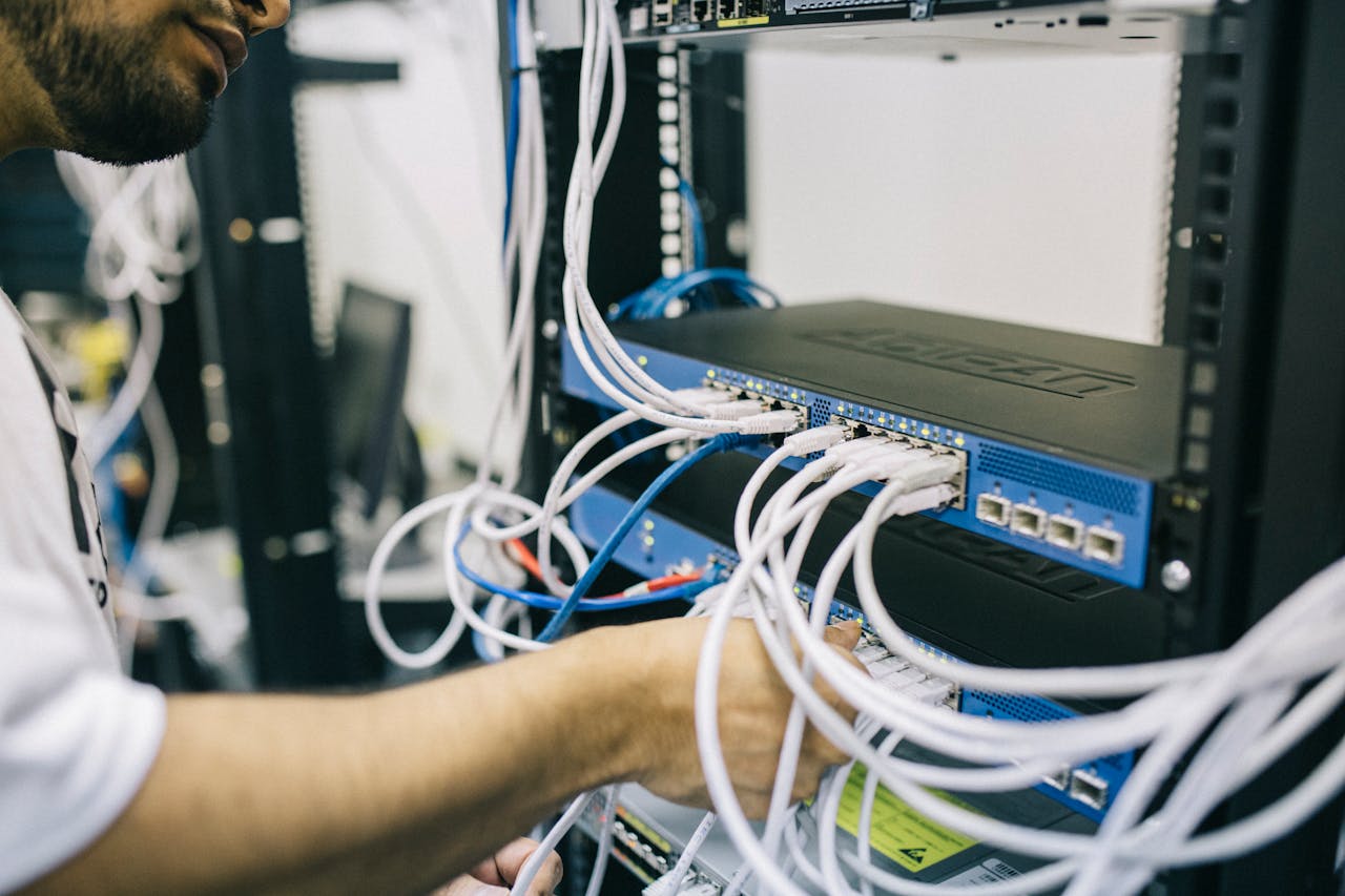 Home An IT professional configuring network cables in a server rack, focusing on Ethernet connections.