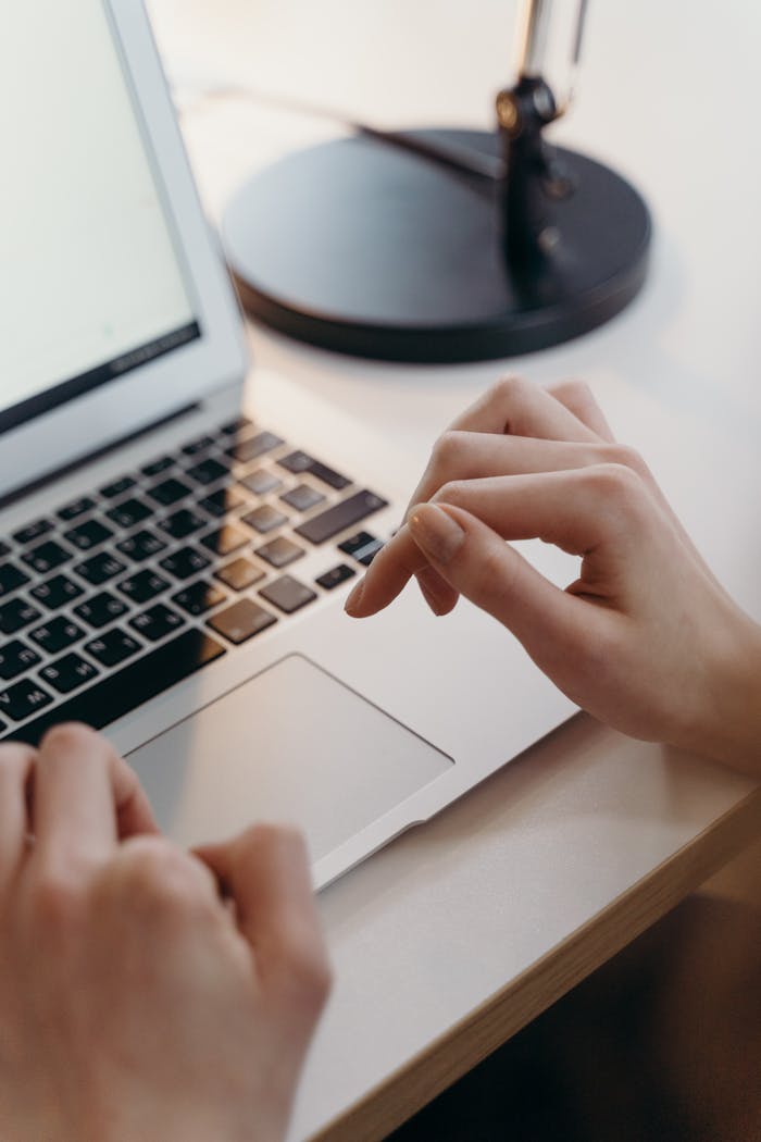 Home Close-up of hands using a laptop's touchpad in an office environment, highlighting focus and technology.